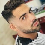 A man with a beard, black eyebrows and a classic pompadour haircut with a contemporary fade.