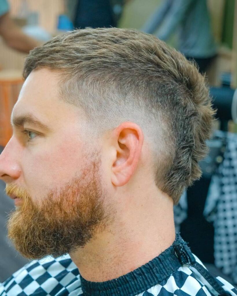 A man with a beard and a burst fade haircut, showcasing a stylish and modern appearance.