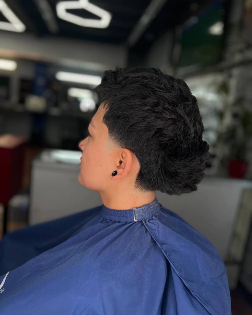 A back view of a blowout taper hairstyle exhibiting a seamless blend from a thick, voluminous top into a smooth taper down the nape, underlining a polished and refined look.