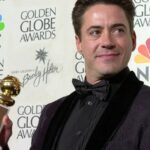 Robert Downey Jr. celebrates winning the Golden Globe for Best Actor in a Drama, showcasing his stylish haircut.