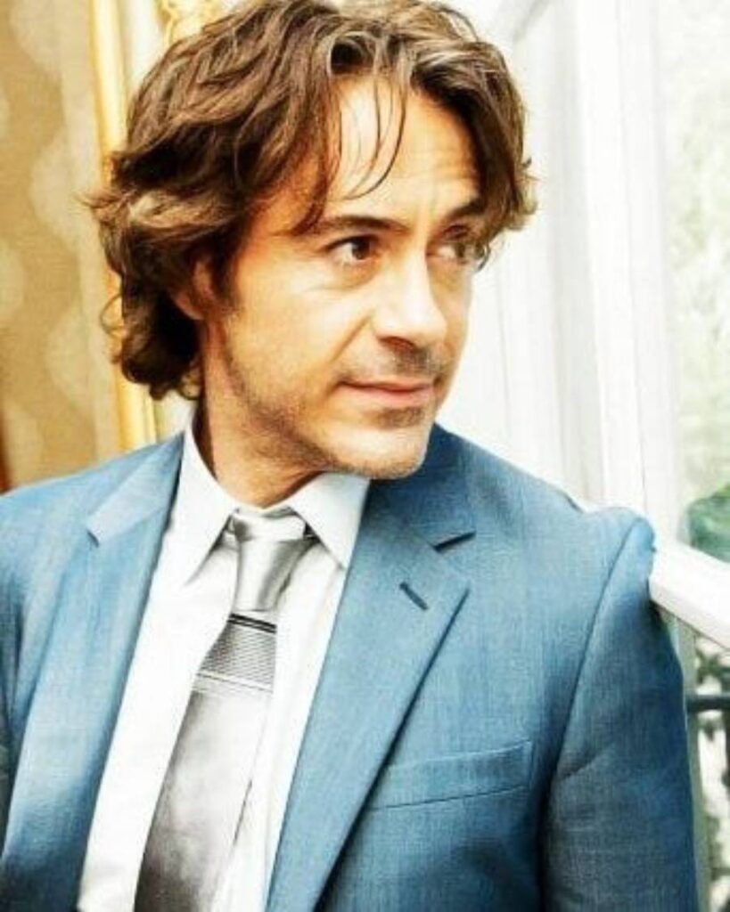 Robert Downey Jr. in a blue suit and tie, showcasing a stylish haircut, exuding confidence and sophistication.