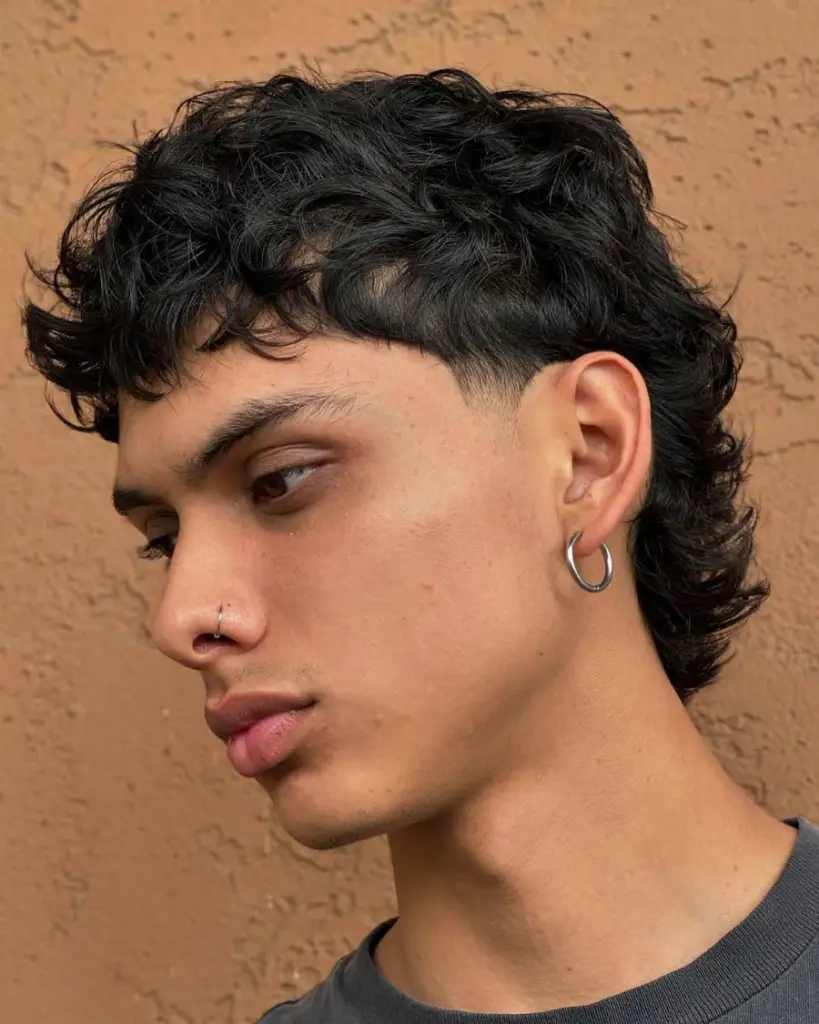 A young man with a fringe haircut, curly hair, and multiple piercings, showcasing a modern and stylish appearance.